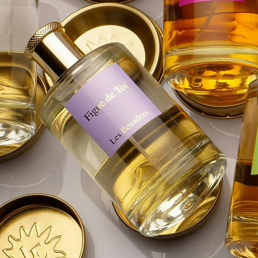 liggende flessen parfum. De middelste fles heeft een lila label met de gouden tekst figue de toi Les Ecuadors