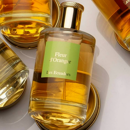 diverse parfumflessen liggend op ronde metelen dekseltjes met in het midden een fles met het label fleur dóranger en het merk les ecuadors