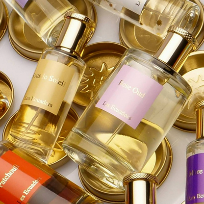 liggende parfumflessen van verschillend formaat e middelste heeft een roze vierkant label met de tekst Rose Oud Les Ecuadors
