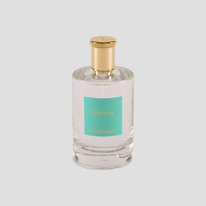 parfumfles tegen een witte achtergrond met gouden dop en een blauw/groen label met de gouden letters Turquoise Les Ecuadors